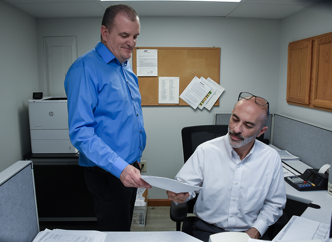 Payroll Pros employee passing a document to a co-worker.