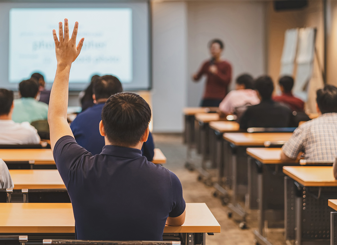 A student raising his hand in a classroom.