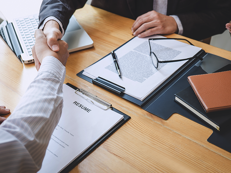 Two individuals shaking hands at a job interview.