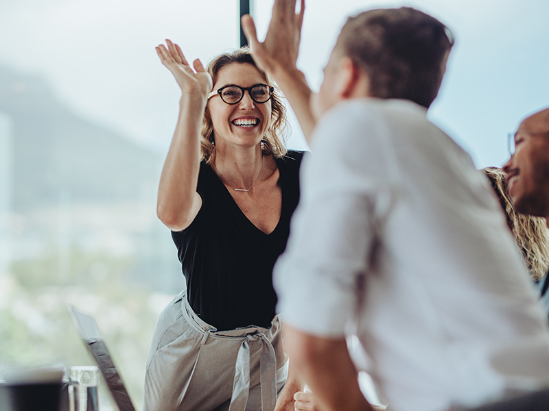 A smiling woman high-fiving another individual.