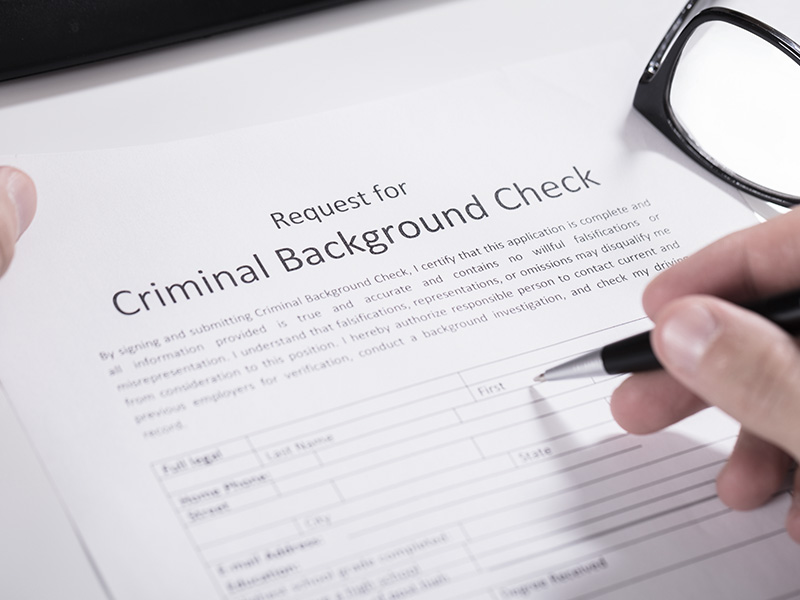 An individual filling out a criminal background check document.