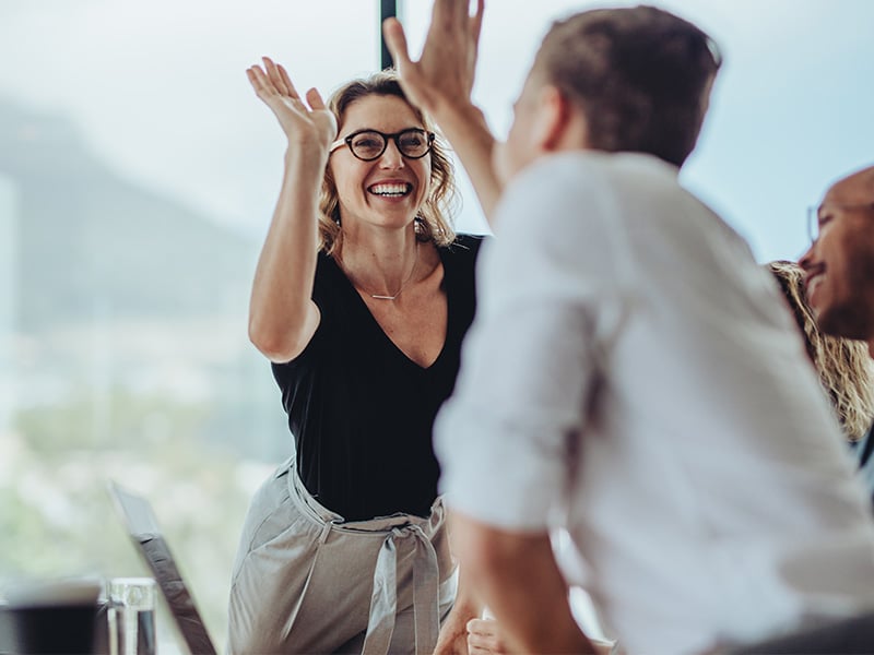 A smiling woman high-fiving another individual.