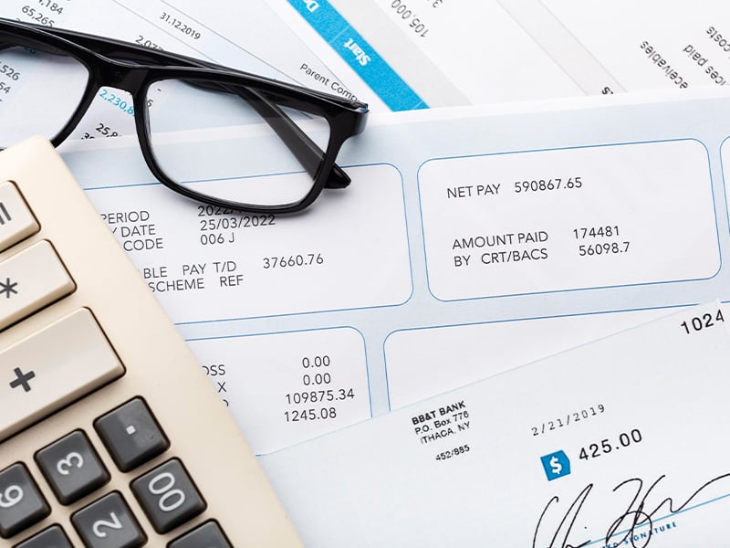 A pile of documents with a calculator and a pair of glasses on top.