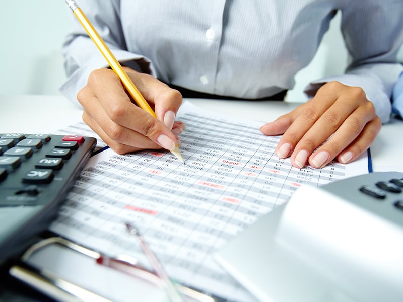 An individual with a pencil in hand writing on a document.